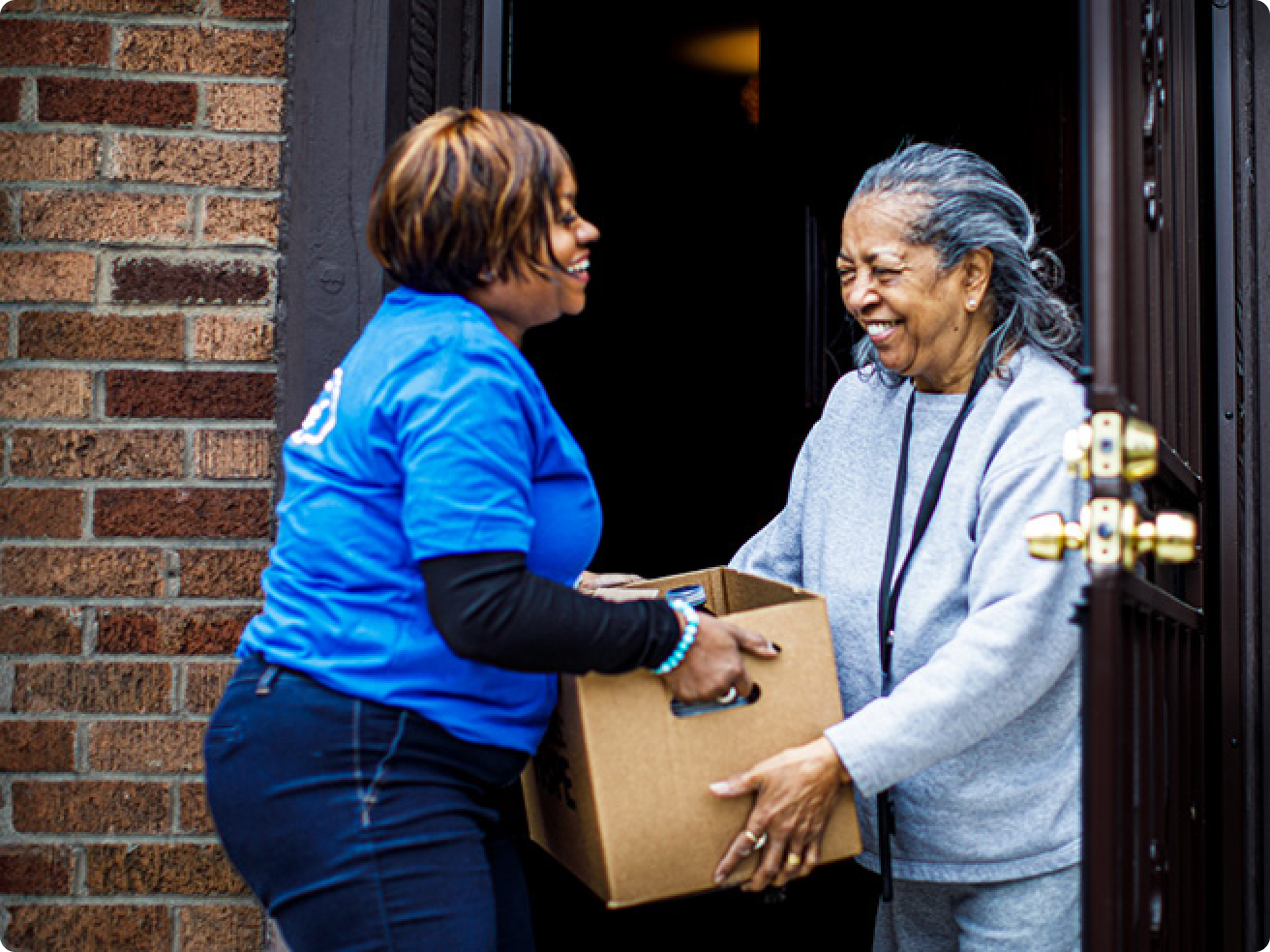 A volunteer giving a box of donations to another person