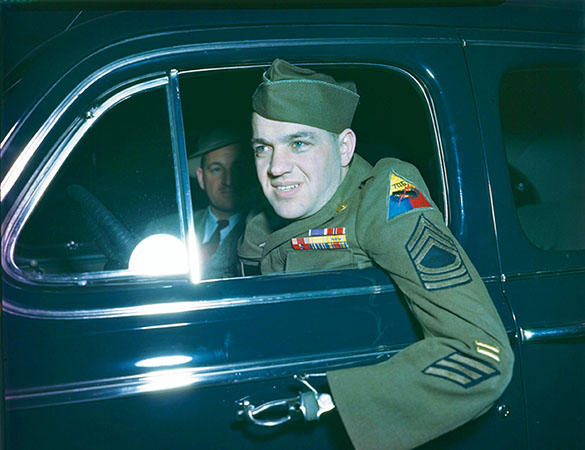 Sgt. Hensel in the driver’s seat of a black car with a passenger. Dressed in his Army uniform he faces out the window with his left arm, a metal upper limb prostheses, out of the car in 1946